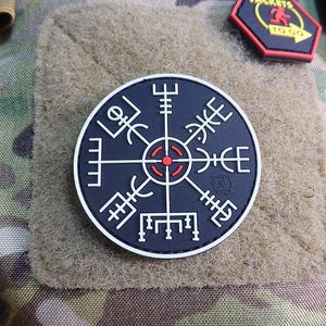 Peut inclure: Patch de compas noir et blanc avec un cercle central rouge. La boussole est entourée d'une bordure blanche et a un fond noir. Le patch est en tissu et a un dos velcro.