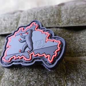 May include: Black and red embroidered patch shaped like the outline of Germany with a bear inside and the text "BERLIN TO GO" in a circle.