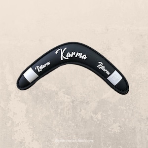 May include: Black boomerang with white stripes and the words "Returns" and "Karma" written on it.