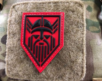 May include: Red and black embroidered patch with a Viking warrior's face in a shield shape.