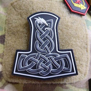 Könnte beinhalten: Schwarz-weiß gestickter Patch eines nordischen Mjolnir-Hammers mit einem Drachenmotiv. Der Patch ist aus einem dicken, strapazierfähigen Material gefertigt und hat einen weißen Rand.