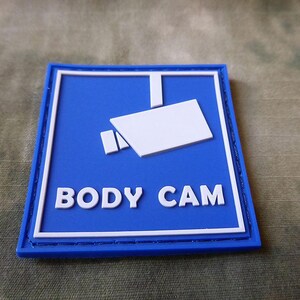 May include: Blue and white patch with a white camera icon and the text "BODY CAM" in white.