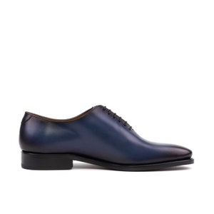 May include: A pair of blue leather lace-up dress shoes with a black sole.