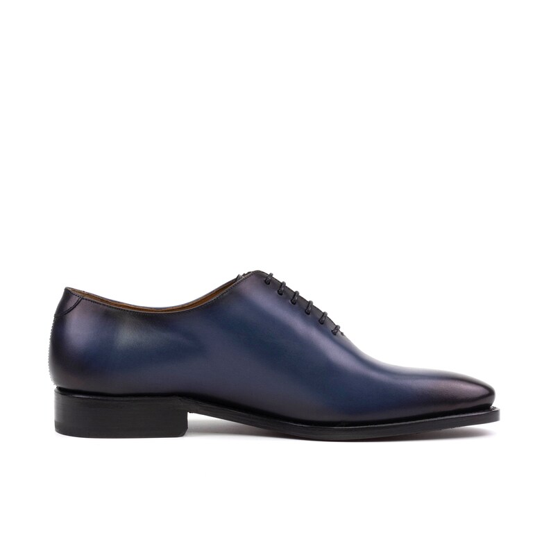 May include: A pair of blue leather lace-up dress shoes with a black sole.