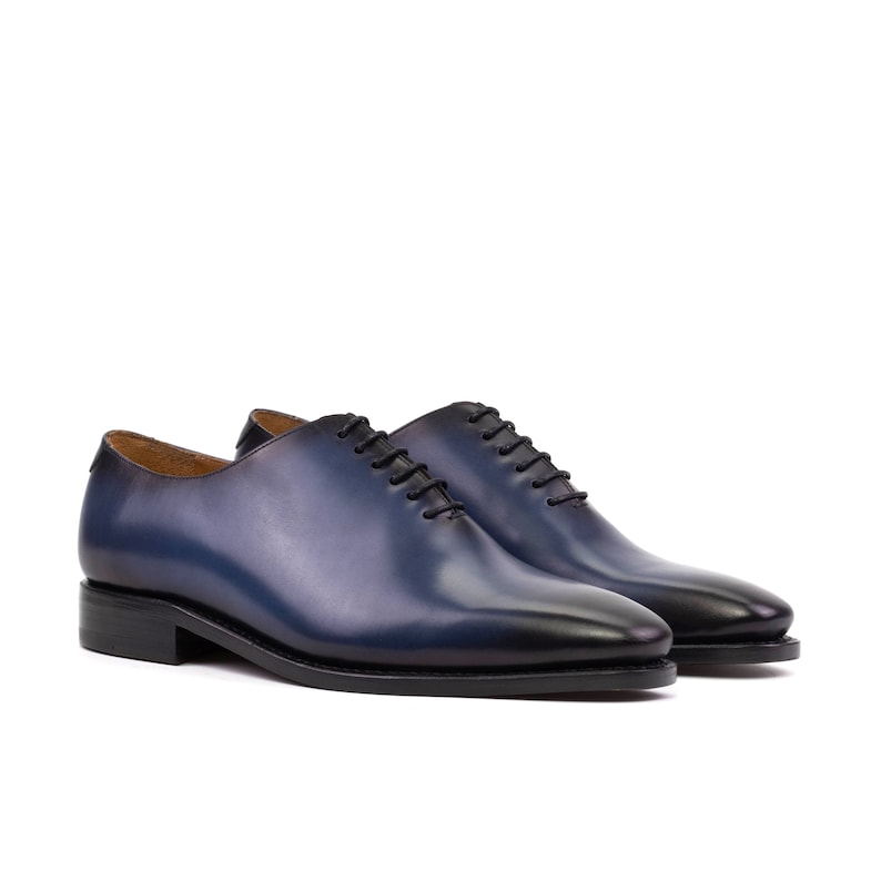 May include: A pair of blue leather lace-up dress shoes with a pointed toe.