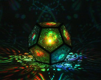 May include: A geometric, multi-faceted lamp with intricate floral patterns. The lamp emits colorful light, casting vibrant patterns on the surrounding surface. The lamp's design features a combination of green, red, and blue hues, creating a mesmerizing visual effect.