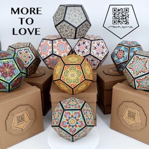 Pu&ograve; includere: Sculture geometriche dodecaedriche con intricati e colorati motivi mandala. L'immagine presenta diversi di questi oggetti decorativi, alcuni appoggiati su scatole marroni. Il testo "MORE TO LOVE" &egrave; visualizzato in alto a sinistra.