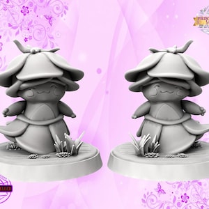 May include: Two gray 3D printed figurines of a mushroom-like creature with a smiling face and a flower-shaped hat. The figurines are standing on a round base with grass and flowers.