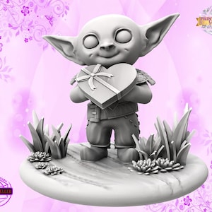 May include: A gray 3D printed figurine of a small, smiling goblin holding a heart-shaped box with a ribbon. The goblin is standing on a round base with grass and flowers.