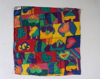 Könnte beinhalten: Ein bunter quadratischer Schal mit einem sich wiederholenden Muster aus Herzen in verschiedenen Farben und Designs. Der Schal ist aus Seide und hat eine weiche, fließende Textur.