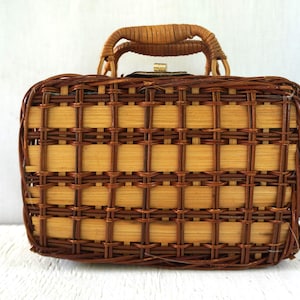 May include: A vintage rectangular wicker handbag with a woven pattern in shades of brown and tan. The bag features a rounded handle and a clasp closure. The bag is a classic accessory.