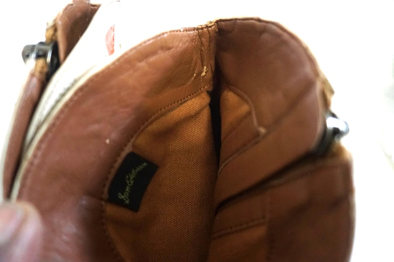 K&ouml;nnte beinhalten: Das Innere eines braunen Lederstiefels mit einem beigefarbenen Stofffutter. Der Stiefel hat einen Rei&szlig;verschluss und ein Etikett mit der Aufschrift "Sam Edelman".