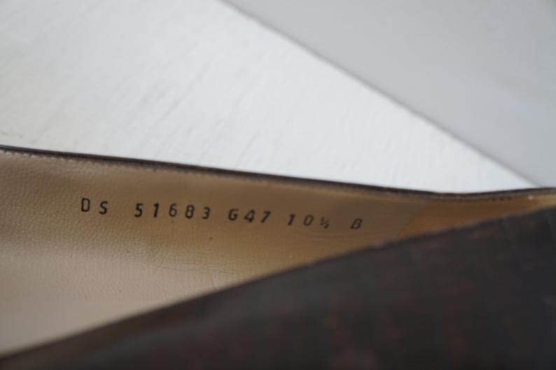 May include: Close-up of the inside of a brown leather shoe with the text "DS 51683 647 10 1/2 B" printed on the insole.