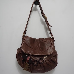 Bolso de hombro Juicy Couture de piel marrón con detalles de cadena, perro Scottie y adornos de lazo