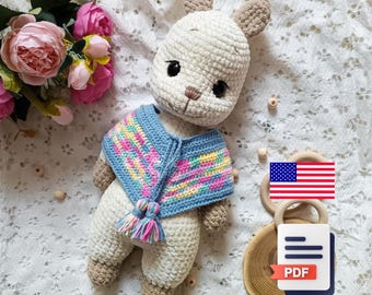 May include: A handmade crochet llama doll with a cream-colored body, brown ears, and a colorful blue and pink poncho. The llama has black eyes and a small brown nose. The doll is approximately 10 inches tall and is a soft toy.