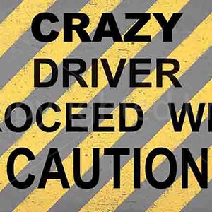 Puede incluir: Una señal de advertencia amarilla y gris con texto negro que dice "Crazy Driver Proceed With Caution". La señal tiene dos triángulos de advertencia amarillos con puntos de exclamación.