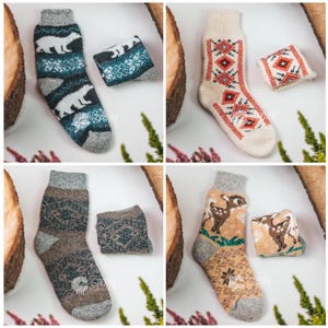 May include: Four pairs of knitted socks with various patterns. One pair features white polar bears on a teal and gray background. Another has a red and white geometric design on a cream base. The third pair has a brown and gray pattern. The last pair has a deer design.