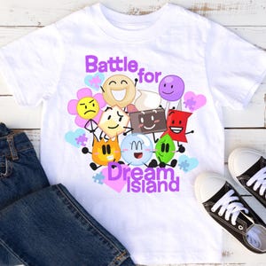 May include: White t-shirt with a colorful graphic of characters from the show "Battle for Dream Island". The graphic includes a variety of shapes and colors, including a red star, a green leaf, a blue circle, and a yellow flower. The text "Battle for Dream Island" is written in purple letters.