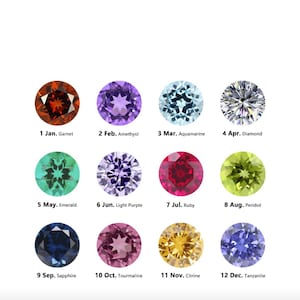 May include: A collection of twelve gemstones, each representing a month of the year. The gemstones include garnet, amethyst, aquamarine, diamond, emerald, light purple, ruby, peridot, sapphire, tourmaline, citrine, and tanzanite.