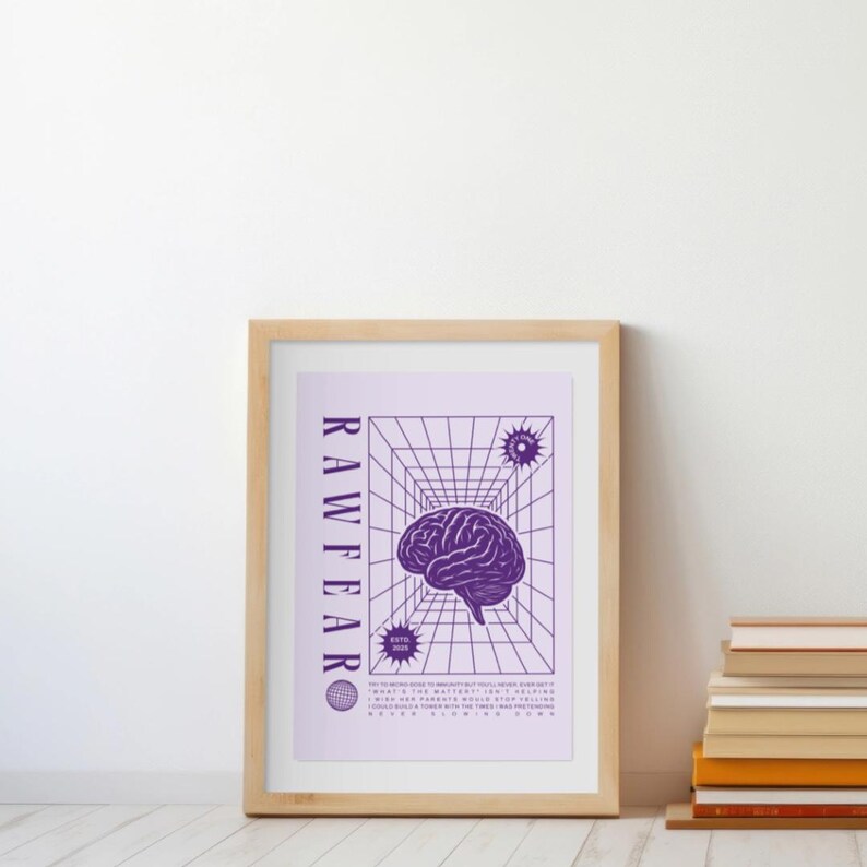 May include: A framed art print featuring a purple brain illustration within a geometric grid. The word "RAWFEAR" is printed vertically on the left side. Additional text and starburst graphics are also present. The frame is made of light-colored wood.