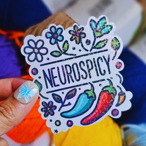 May include: White sticker with a colorful floral design and the text "Neurospicy". The sticker features a red and green chili pepper, a blue and green chili pepper, and a yellow chili pepper.