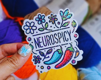 May include: White sticker with a colorful floral design and the text "Neurospicy". The sticker features a red and green chili pepper, a blue and green chili pepper, and a yellow chili pepper.