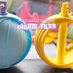 May include: Two armadillo-shaped spinners in the image. One is light blue with a purple top, the other is yellow. The text "ARMADILLO SPINNER DIGITAL FILES" is displayed in the center of the image.