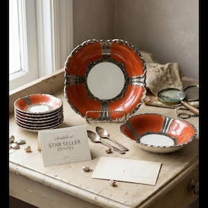 May include: A collection of orange and silver-rimmed plates and bowls. The plates are stacked, and a large plate is displayed on a stand. The text "Available at STAR SELLER ESTATES" is on a card.