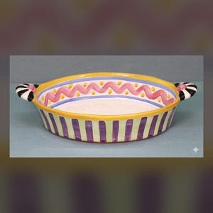 May include: A round ceramic baking dish with two side handles. The exterior features vertical purple and light green stripes. The interior rim is decorated with a yellow border, a blue line, and a pink wavy line with small yellow dots.