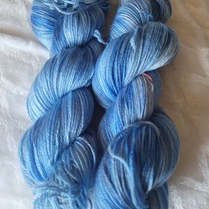 Könnte beinhalten: Zwei Knäuel blaues Garn mit einem Farbverlauf von hellblau zu dunkelblau. Das Garn ist weich und flauschig und perfekt zum Stricken oder Häkeln.