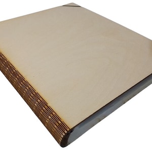 Può includere: Un libro di legno vuoto con una spina dorsale marrone e una copertina marrone chiaro. Il libro è chiuso e ha un design semplice.