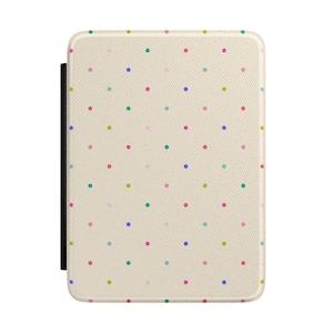 Op de afbeelding: Een rechthoekige e-reader hoes met een getextureerd crèmekleurig oppervlak met een herhalend patroon van kleine, gelijkmatig verdeelde stippen in diverse kleuren, waaronder blauw, groen, roze, geel en rood, met een zwarte rug aan de linkerzijde.