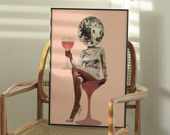 May include: A framed print of a woman with a disco ball head holding a glass of pink liquid. The woman is wearing a silver dress and sitting on a stool. The background is a light pink color.