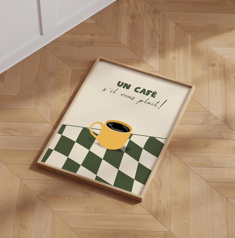 May include: A framed print with a yellow coffee cup on a black and white chequered background. The text reads "Un Caf&eacute; s'il vous pla&icirc;t!"