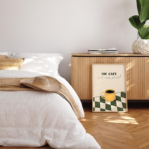 May include: A framed print featuring a yellow coffee cup and the text "UN CAF&Eacute; s'il vous pla&icirc;t!" against a green and white chequered background.