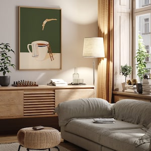 May include: A living room interior with a light gray sofa, a wooden cabinet, a wicker ottoman, and a floor lamp with a beige lampshade. A framed print of a stylized illustration of a person diving into a coffee mug hangs on the wall.