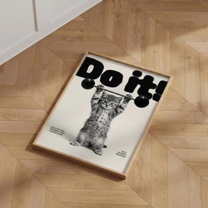 May include: Framed poster featuring a kitten lifting a barbell. The poster has the words "Do it!" in large black letters at the top. Below the kitten, the text reads "Do it or don't whatever." The poster is in a wooden frame.