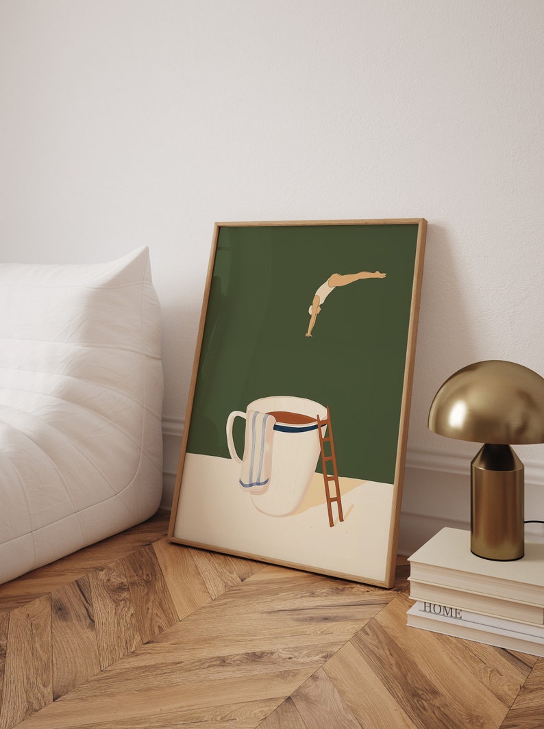 May include: A framed illustration of a person diving into a large white mug with a brown liquid inside. The mug has a blue and white striped towel draped over the side. The background is a dark green color.