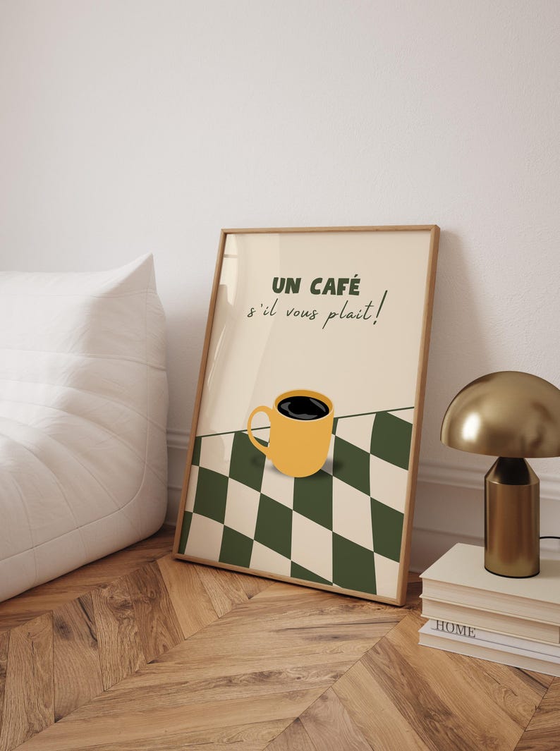 May include: A framed print with a yellow coffee cup on a black and white chequered background. The text on the print reads "UN CAF&Eacute; s'il vous pla&icirc;t!"