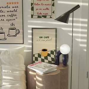 May include: A framed poster with a black and white chequered background and a yellow coffee cup with the text "UN CAF&Eacute; s'il vous plait!" in red and black lettering.