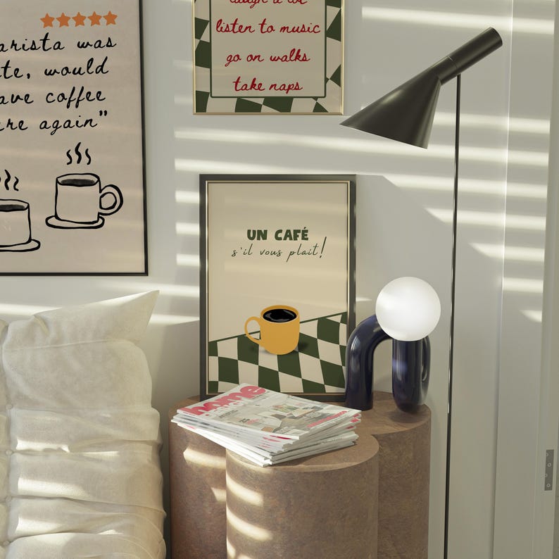 May include: A framed poster with a black and white chequered background and a yellow coffee cup with the text "UN CAF&Eacute; s'il vous plait!" in red and black lettering.