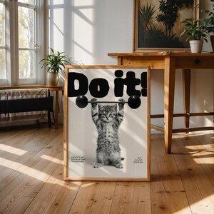 May include: A framed poster features a gray tabby kitten lifting a barbell with the words "Do it!" in bold black letters. The poster includes the phrases "Even cats are stronger than your excuses" and "Do it or don't whatever."