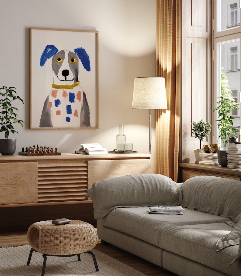May include: A living room interior with a light grey sofa, a wooden cabinet, a wicker stool, a floor lamp, and a framed illustration of a dog with blue ears and a colourful scarf.
