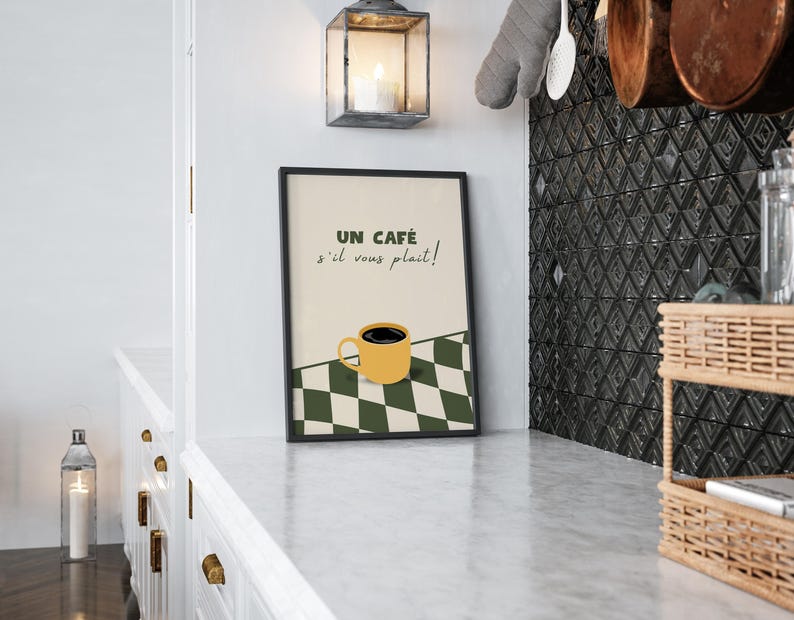 May include: A black framed print with a white and green chequered background. The print features a yellow coffee cup with black coffee and the text "Un caf&eacute; s'il vous pla&icirc;t!" in French.