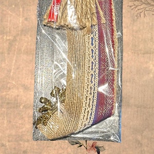 May include: A set of tassels and trims for crafting and decorating. The set includes a variety of colors and textures, including red, blue, white, and gold. The tassels are made of jute and the trims are made of fabric and lace. The set is packaged in a clear plastic bag with a label that says "Tassels Quasten Dekoration".