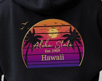Puede incluir: Sudadera con capucha negra con un gráfico dorado de una puesta de sol con palmeras y el texto "Aloha State Est. 1959 Hawaii".