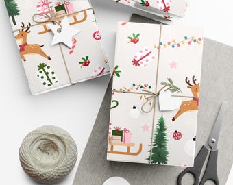 以下が含まれることがあります： トナカイ、クリスマスツリー、ギフトボックスのイラストが描かれた、お祝いのクリスマスをテーマにしたギフト包装紙。 ギフトは紐で結ばれ、空白のタグで飾られています。 紐の巻きとハサミも付いています。