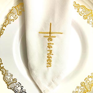 May include: White linen napkin with a gold embroidered cross and the word "Heaven" on a white plate with a gold decorative border.