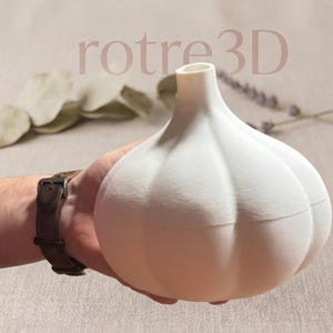 Könnte beinhalten: Ein weißer, knoblauchförmiger dekorativer Behälter. Der Behälter hat eine strukturierte Oberfläche und eine kleine Öffnung oben. Der Text "rotre3D" ist im Hintergrund sichtbar.