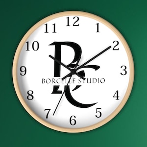 May include: A round wall clock with a light wood frame. The clock face is white with black numerals and hands. The clock features the text "BORCELLE STUDIO" and a stylized black logo.